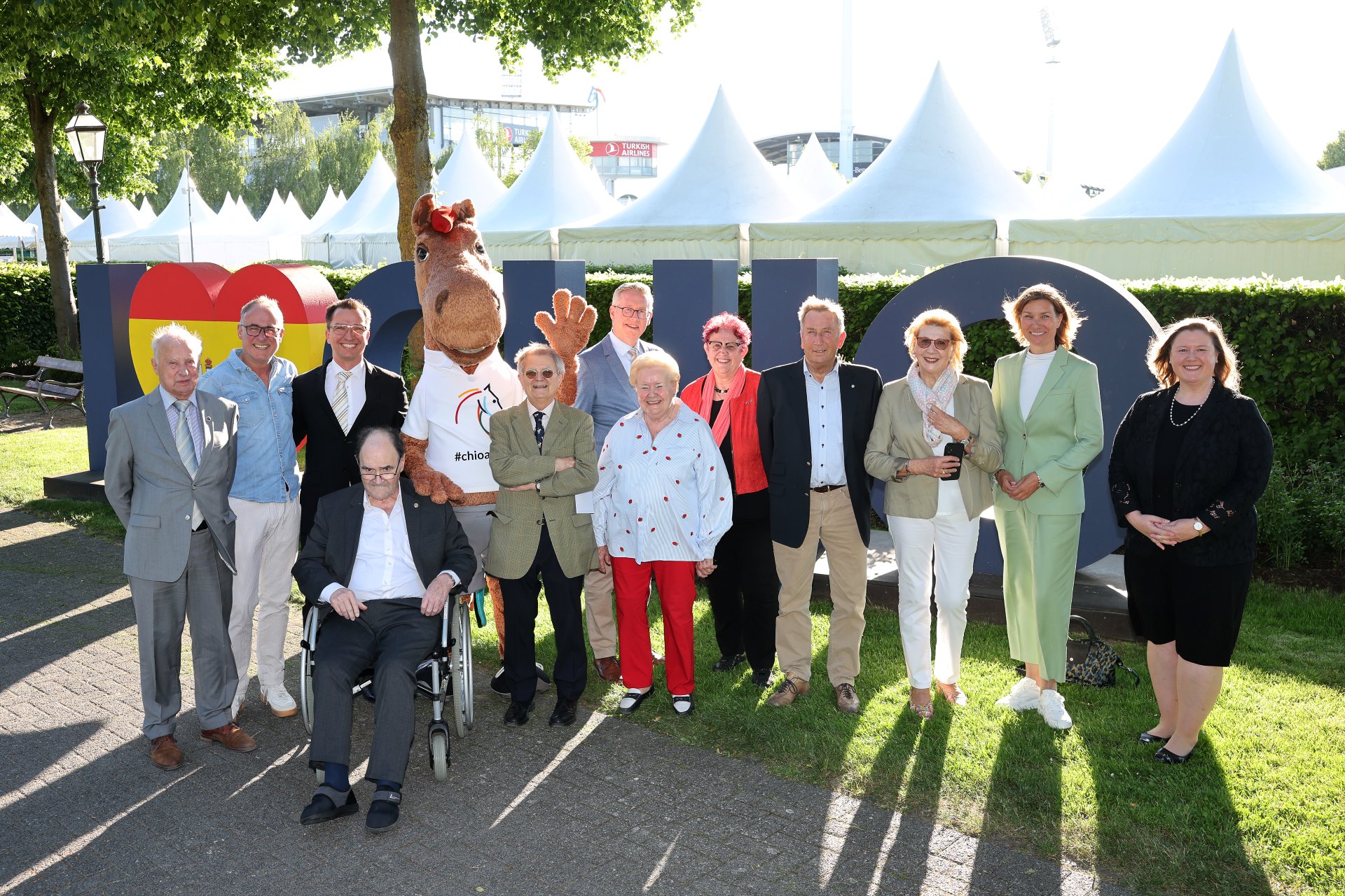 ALRV-Präsidentin Stefanie Peters in einem hellgrünen Hosenanzug und CHIO Aachen-Maskottchen Karli stehen zusammen mit den Jubilaren vor dem Schriftzug des I Love CHIO-Selfiespots. Geehrt wurden Katrin-Elisabeth Uttermann, Brigitte Maria Wienand, Oliver Henn, Heiner Höfken, Prof. Dr. Rudolf Lütticken, Christian Mourad, Franz-Josef Schell, Prof. Dr. Helmut Thoma, F. Xaver Klinkenberg für 25 Jahre Mitgliedschaft; Theo Thomas, Dr. Werner Becker, Bernd Geisler, Christian Lücker, Carl August Witt, Parkhotel Quellenhof Aachen für 40 Jahre Mitgliedschaft; Ruth Crumbach-Trommler für 60 Jahre Mitgliedschaft sowie Werner Leuchter für 70 Jahre Mitgliedschaft.