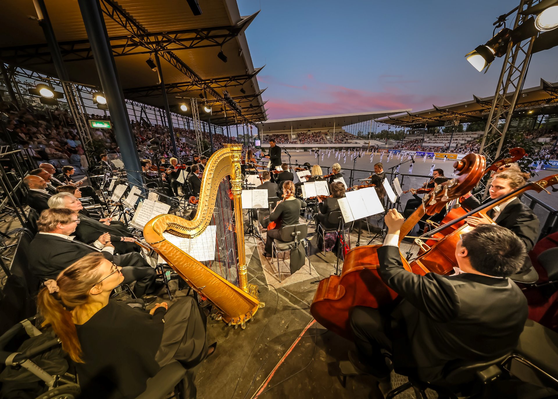 Blick aus der Mitte des Sinfonieorchester Aachen auf die Tänzer in der Mitte des ausverkauften Dressurstadions beim Konzert „Pferd & Sinfonie“